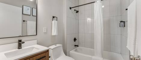 A modern bathroom with a white sink, toilet, and bathtub.