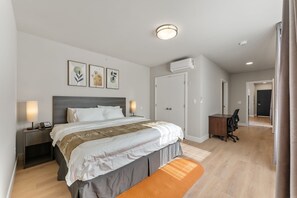 Une chambre moderne avec un grand lit, des tables de chevet, un bureau et un appareil de climatisation.