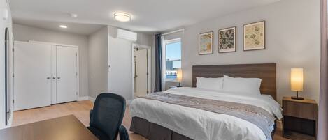Una habitación de hotel con cama, escritorio, silla y una obra de arte en la pared.