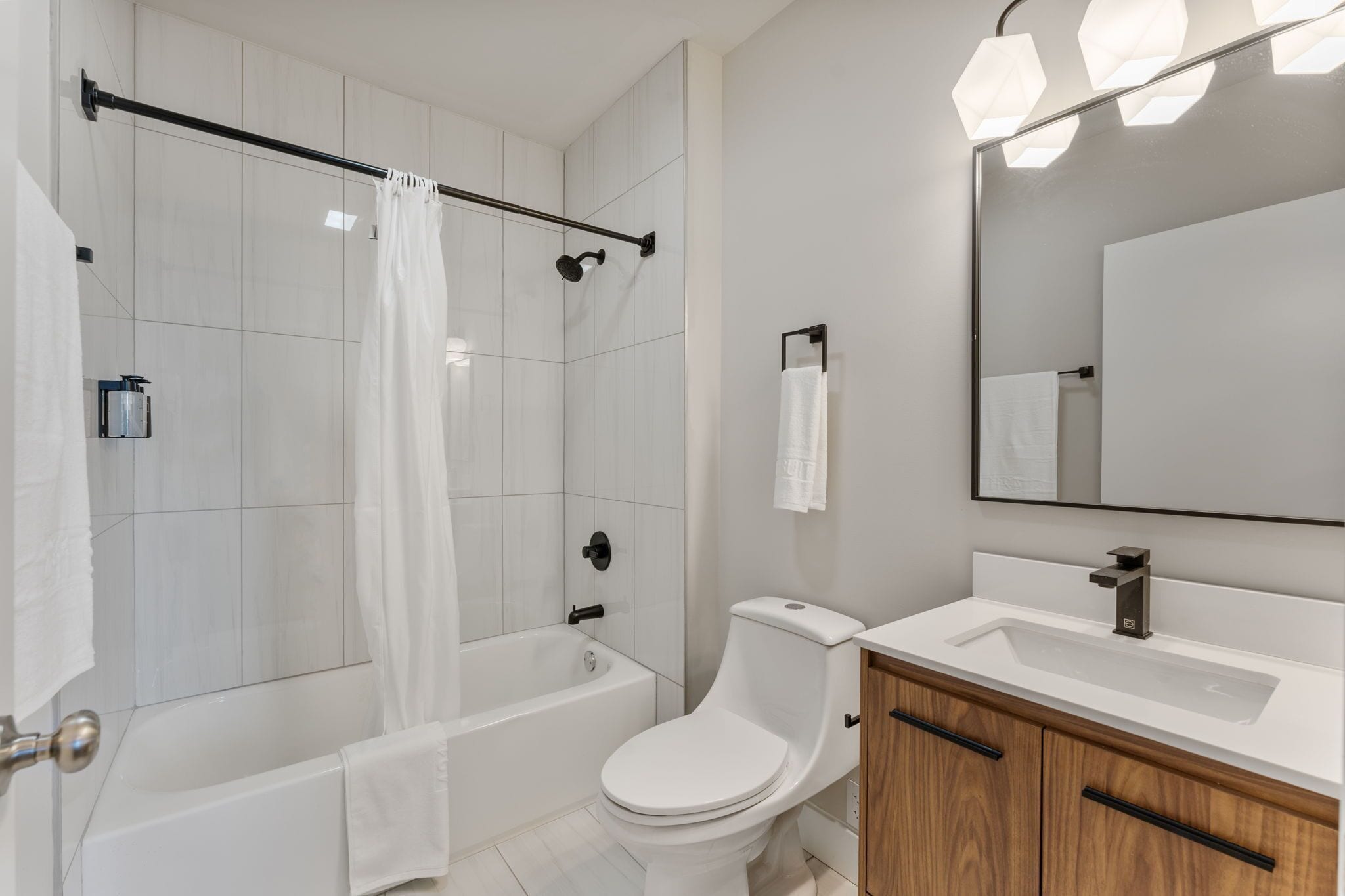 A modern bathroom with a shower, toilet, and sink.