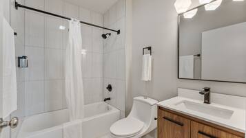 A modern bathroom with a shower, toilet, and sink.