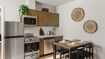 A modern kitchen with stainless steel appliances, wooden cabinets, and a dining area with a table and chairs.