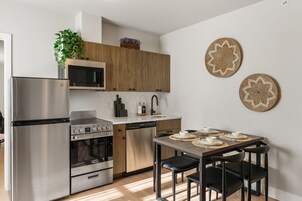 Una cocina moderna con electrodomésticos de acero inoxidable, armarios de madera y un comedor con mesa y sillas.