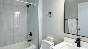Een moderne badkamer met een badkuip, toilet en wastafel.