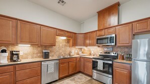 A modern kitchen with wooden cabinets, stainless steel appliances, and a tiled backsplash.