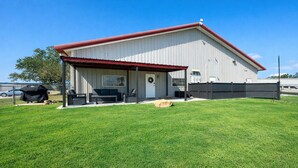 A covered patio area with outdoor furniture, a barbecue grill, and a fenced yard.