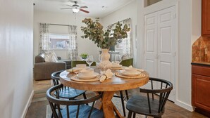 A dining area with a round wooden table, four chairs, and a vase with flowers.