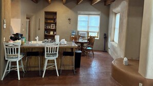 A kitchen with a central island, wooden chairs, and a window with blinds. - Charming 1.5 Bedrooms, 1600 sq. Ft Guest House Views/Yard W/D High Ceilings  (Santa Fe)