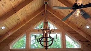 Une cabane en bois avec un coin repas, de grandes fenêtres et un lustre.