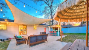 An outdoor patio with wicker furniture, a wooden table, and string lights. - Walk to Beach, Ping Pong, King Beds, Sleeps 6 (Muskegon)