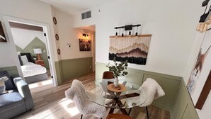 A modern dining area with a glass table, white fluffy chairs, and a vase of flowers. - Three Peaks Getaway - sleeps 4 (Canmore)