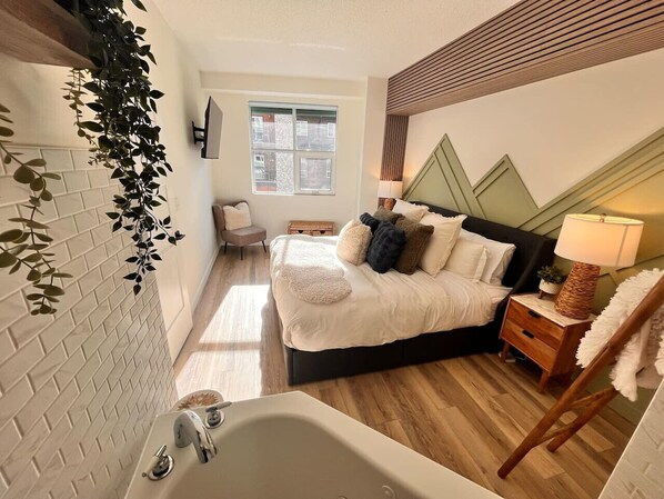 Ein Schlafzimmer mit Bett, Nachttisch, Lampe und Blick ins Freie.