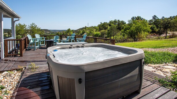 A hot tub on a wooden deck with chairs and a view of the landscape. - Hot Tub Retreat by Wine Country (Fredericksburg)