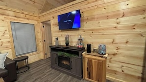 Une pièce aux murs lambrissés, avec un téléviseur fixé au mur, un petit meuble et un coin salon comprenant un canapé et une table basse.
