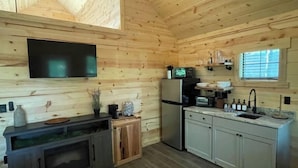 Une cuisine compacte avec des murs en bois, un téléviseur encastré, un réfrigérateur et un évier.