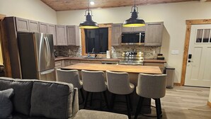 A modern kitchen with a central island, stainless steel appliances, and wooden cabinetry. - NEW 3-bedroom cabin in beautiful Emily, MN.  Located right on the trails! (Emily)