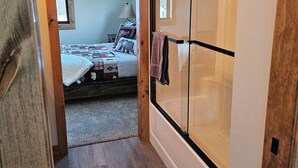 A hallway leading to a bedroom with a bed, a nightstand, and a window. - NEW 3-bedroom cabin in beautiful Emily, MN.  Located right on the trails! (Emily)
