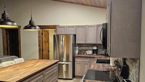 A modern kitchen with wooden ceiling, stainless steel appliances, and a central island. - NEW 3-bedroom cabin in beautiful Emily, MN.  Located right on the trails! (Emily)