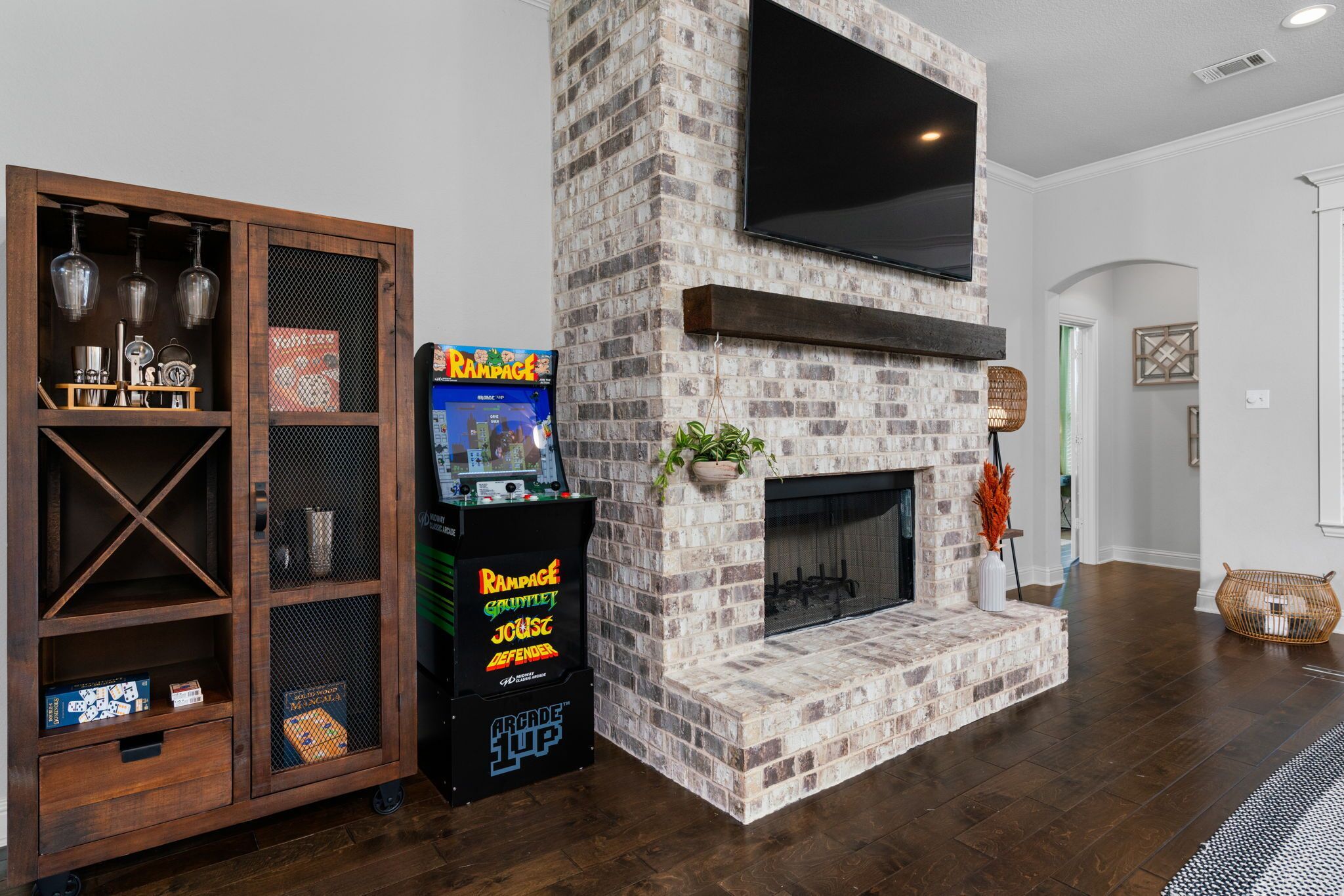 Una sala de estar con chimenea de ladrillo, televisor montado y mueble de madera con estantes.
