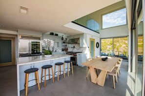 Una cocina moderna con una isla central, taburetes de bar, una mesa de comedor y vistas al exterior.