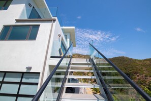 Un edificio moderno con una escalera de cristal que lleva a un balcón con vistas a un paisaje montañoso.