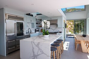 Una cocina moderna con encimeras de mármol, electrodomésticos de acero inoxidable y una isla grande con taburetes de bar.