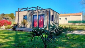 Ein modernes Haus mit einer Holz-Pergola, umgeben von einem gepflegten Garten mit verschiedenen Pflanzen und einer Rasenfläche.