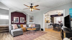 A modern living room with a grey sofa, wooden coffee table, and a ceiling fan.