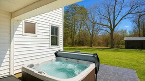 Ein Whirlpool vor einem Haus mit Blick auf Bäume und eine Rasenfläche.