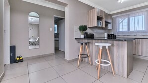 A modern kitchen with a wooden island, two bar stools, and a large mirror. - Luxury & Secure apartment - Fourways (Fourways)