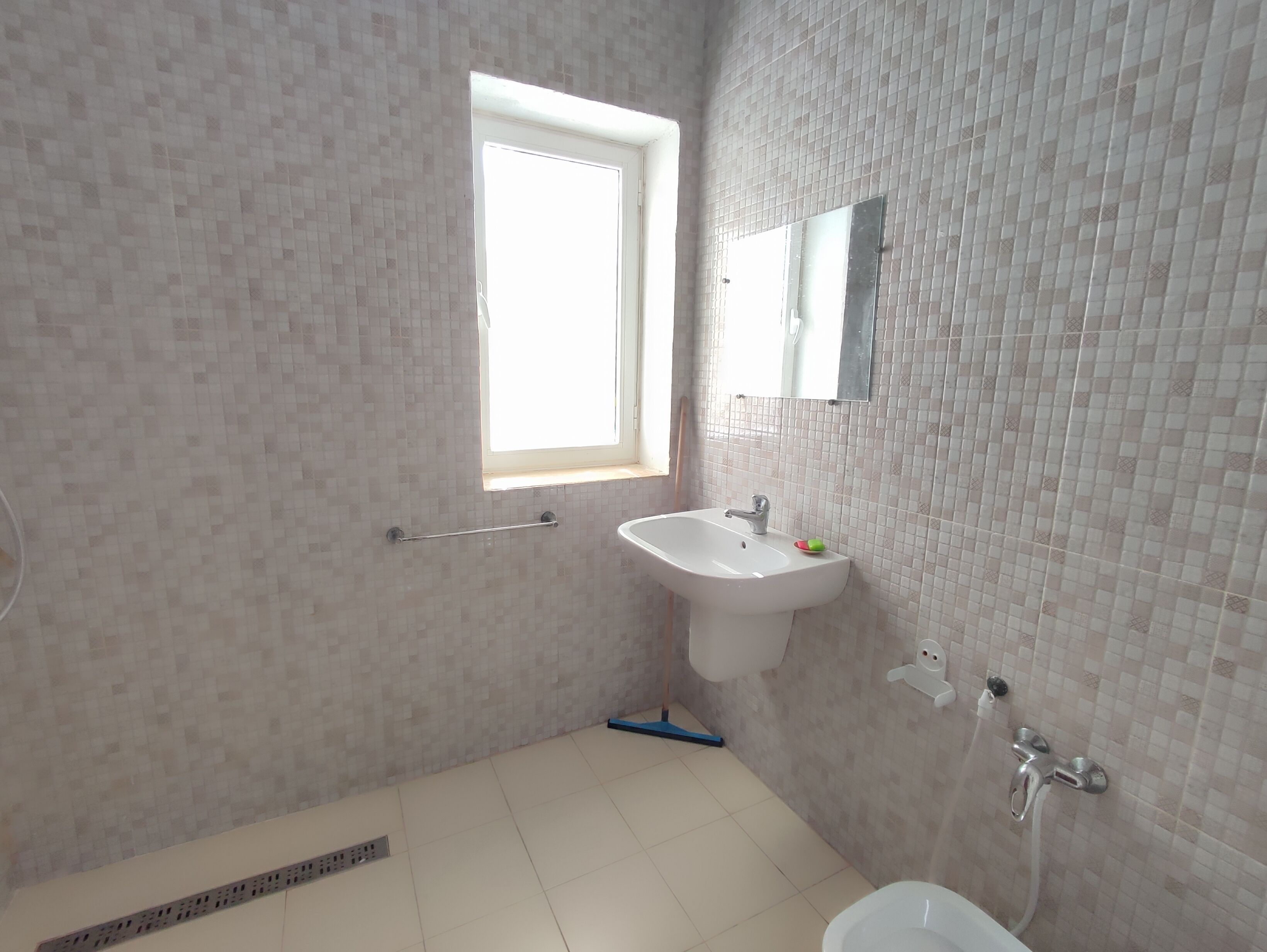 A bathroom with a window, a sink, a mirror, and a shower.