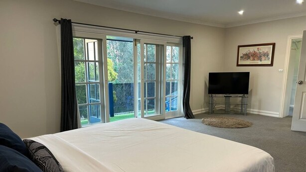 Een slaapkamer met een groot bed, een televisie en een schuifdeur naar een tuin.