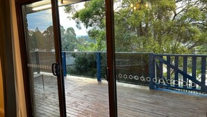 Uitzicht vanuit een kamer met een schuifdeur naar een terras met een blauwe balustrade.