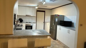 Een moderne keuken met witte kasten, een roestvrijstalen koelkast en een inbouwoven.
