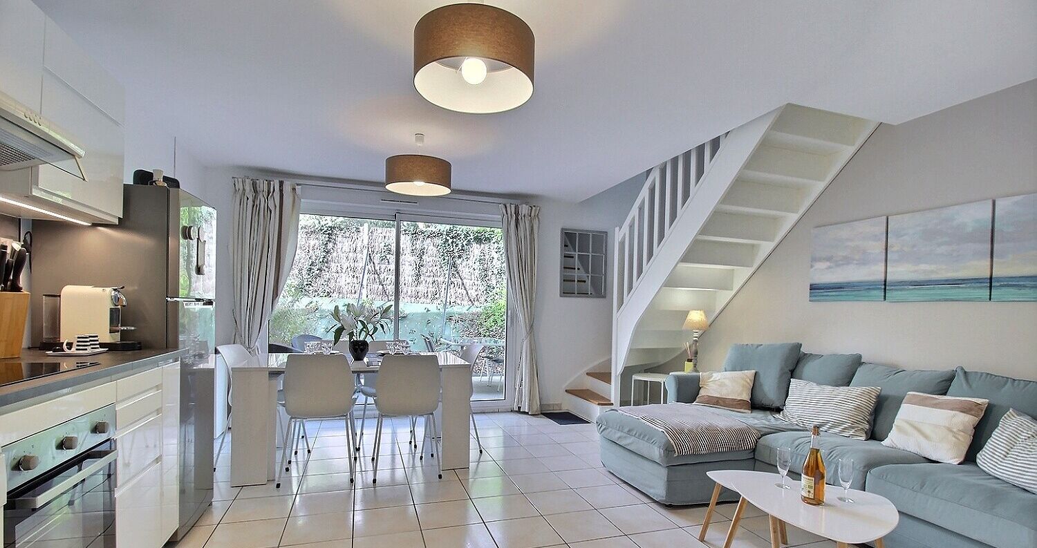 A modern living space with a kitchen, dining area, and a staircase leading to an upper level.