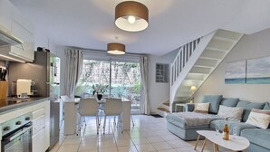 A modern living space with a kitchen, dining area, and a staircase leading to an upper level. - House Six - PLENEUF VAL ANDRE (PLENEUF VAL ANDRE)
