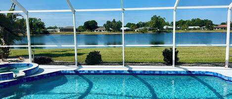 A clear blue swimming pool with a view of a lake and houses in the background.