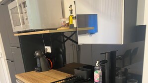 Een kleine keuken met een magnetron, spoelbak en een koelkast.