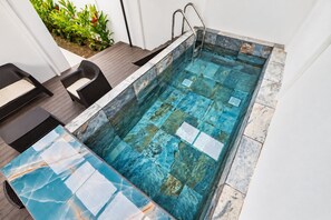 A rectangular swimming pool with a clear water surface, surrounded by a tiled deck with a mix of blue and white tiles.