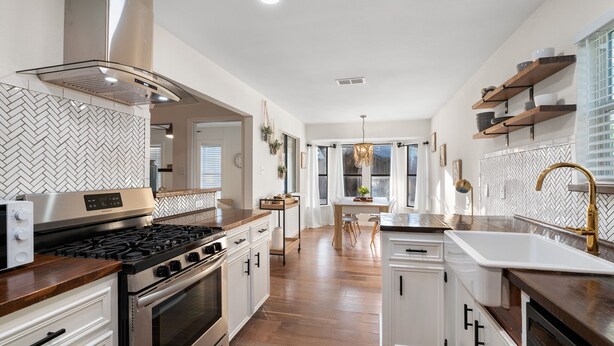 A modern kitchen with stainless steel appliances, white cabinetry, and a herringbone-patterned backsplash. - Charming & Bright W Lounging Pool (Round Rock)