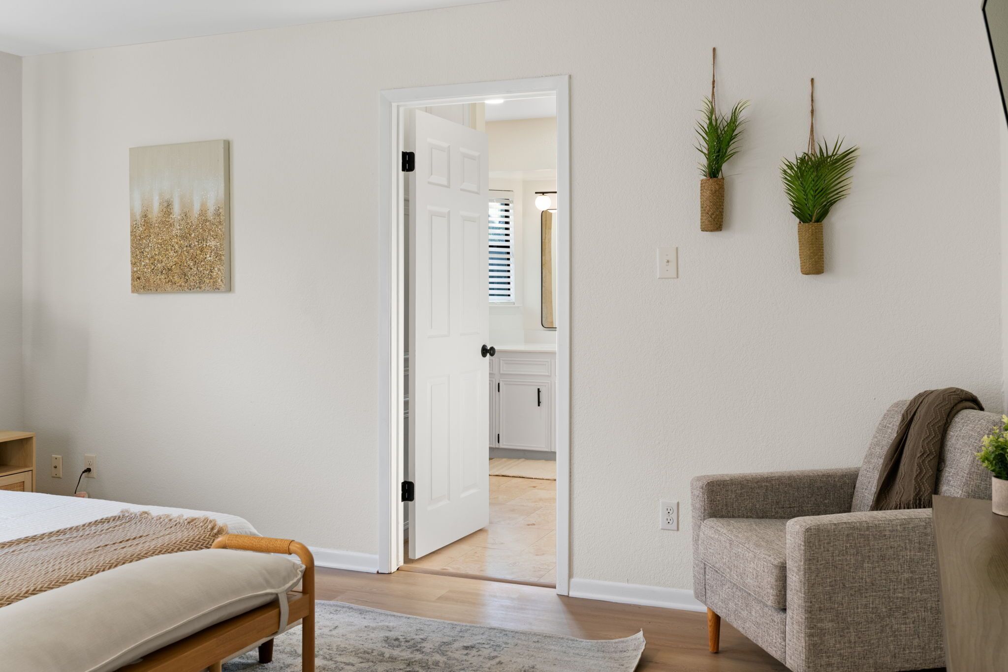Une chambre à coucher comprenant un lit, une table de chevet, une chaise et une porte donnant sur une salle de bain.
