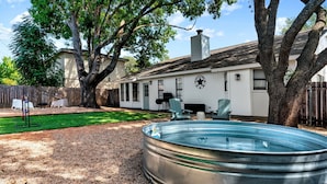 A backyard with a swimming pool, a wooden deck, and a house with a star emblem. - Charming & Bright W Lounging Pool (Round Rock)