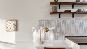 A kitchen with a white countertop, wooden chair, and a herringbone-patterned backsplash. - Charming & Bright W Lounging Pool (Round Rock)