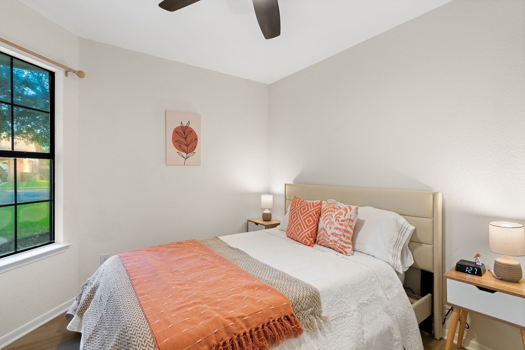 A neatly arranged bedroom with a bed, bedside tables, and a window.