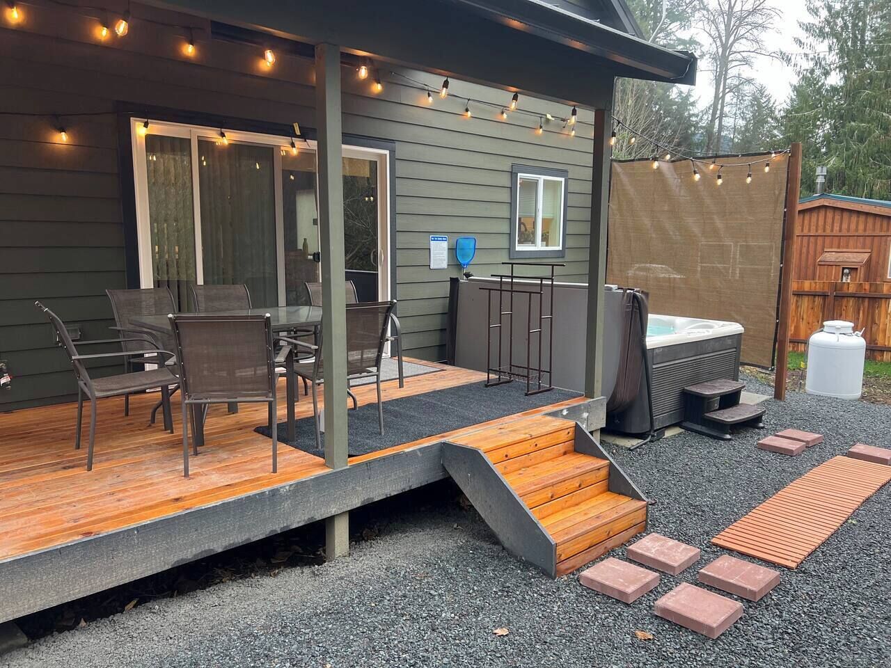 A covered patio with outdoor seating, a hot tub, and a wooden deck.