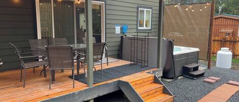 A covered patio with outdoor seating, a hot tub, and a wooden deck.