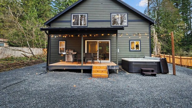 A two-story house with a covered patio, a hot tub, and a deck.