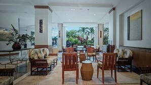 A spacious lobby with wooden furniture, a central table, and a view of greenery outside. - Waikiki ocean view studio, easy walk to beach, shopping, restaurants (Honolulu)