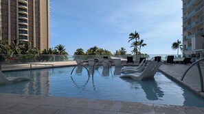 A swimming pool with lounge chairs and a 'No Diving' sign, surrounded by palm trees and buildings. - Waikiki ocean view studio, easy walk to beach, shopping, restaurants (Honolulu)