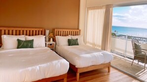 A bedroom with two beds, a ceiling fan, a nightstand with a vase, and a view of the ocean. - Waikiki ocean view studio, easy walk to beach, shopping, restaurants (Honolulu)